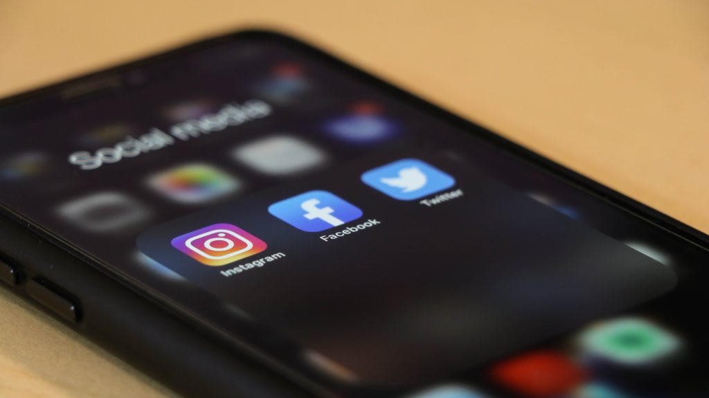 Phone displaying the social media app icons for Instagram, Facebook and Twitter