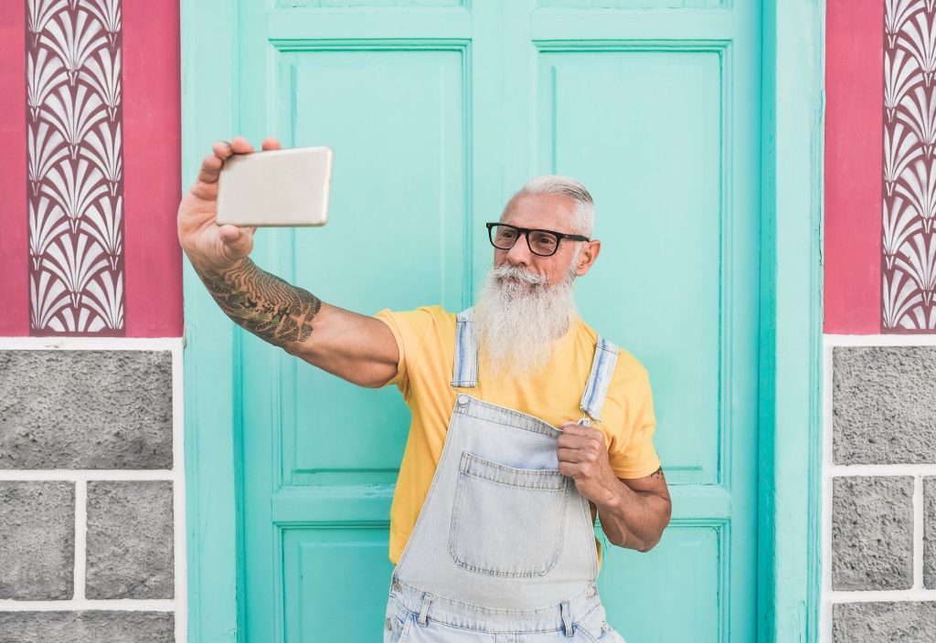 Trendy senior man taking a selfie using mobile phone
